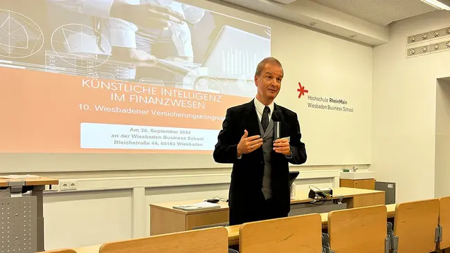 Prof. Dr. Matthias Müller Reichart steht mit einem Mikrofon in der Hand in einem Hörsaal