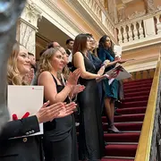 Absolvent:innen des Fachbereichs Wiesbaden Business School stehen mit ihren Urkunden auf einer Treppe.