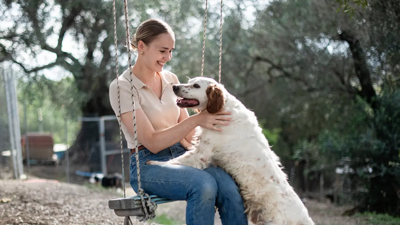 Zerina Kaps auf einer Schaukel, Hund angelehnt