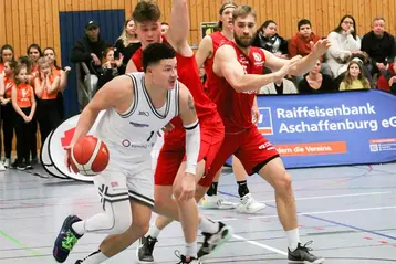 In einer Sporthalle spielen zwei Teams gegeneinander Basketball