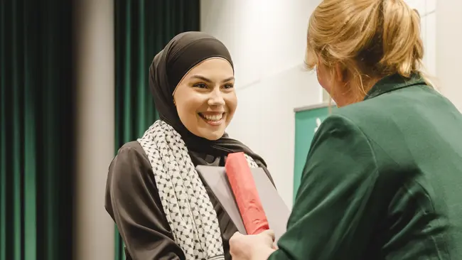 Abschlussfeier 2024. Zwei Frauen geben sich die Hand zur Gratulation 