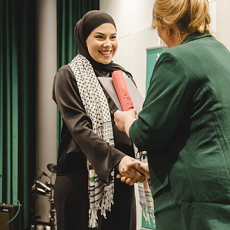 Abschlussfeier 2024. Zwei Frauen geben sich die Hand zur Gratulation 