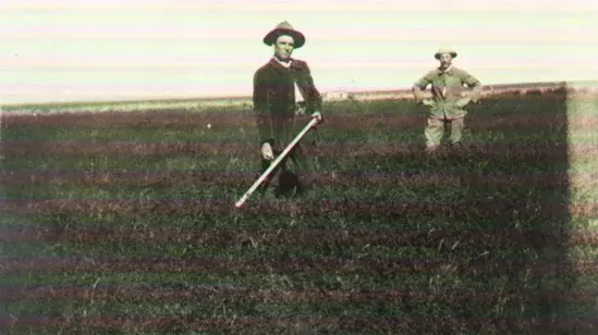 Ein schwarz-weiß Foto ist abgebildet mit zwei Männern, die in einem Feld stehen