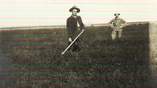 Ein schwarz-weiß Foto ist abgebildet mit zwei Männern, die in einem Feld stehen