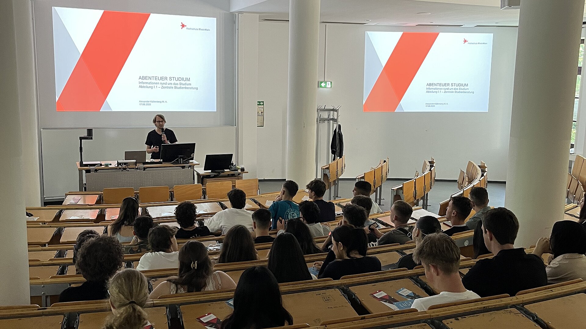 Schüler:innen im Hörsaal der Wiesbaden Business School werden über die Hochschule RheinMain durch die Zentrale Studienberatung infomiert.
