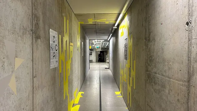Blick in einen Gang. An den Wänden sind Gestaltungselemente der Ausstellung Werkschau Wiesbaden zu erkennen.