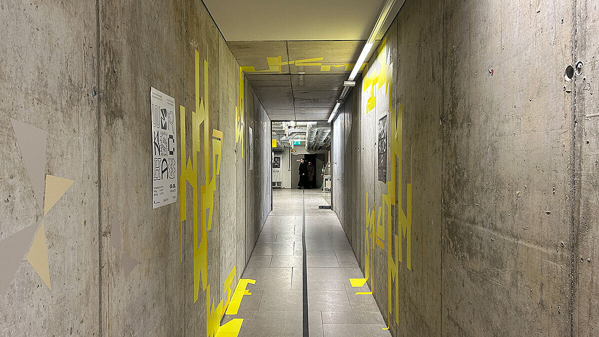 Blick in einen Gang. An den Wänden sind Gestaltungselemente der Ausstellung Werkschau Wiesbaden zu erkennen.