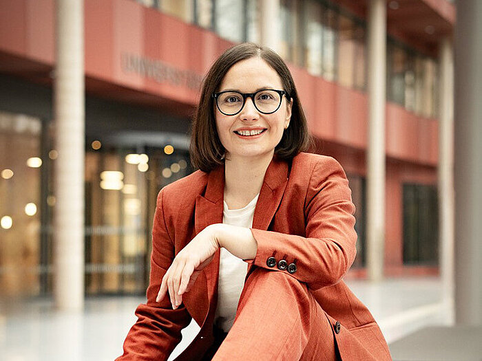 Prof. Dr. Marion Koelle sits on a bench and smiles into the camera