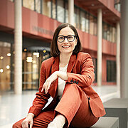 Prof. Dr. Marion Koelle sits on a bench and smiles into the camera