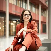 Prof. Dr. Marion Koelle sits on a bench and smiles into the camera