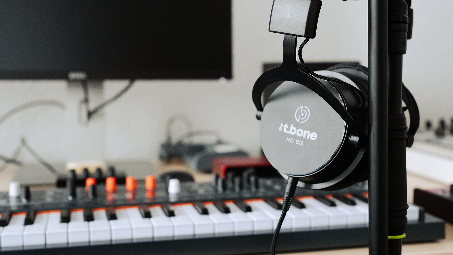 Musikproduktion Kopfhörer mit Keyboardmixer im Hintergrund