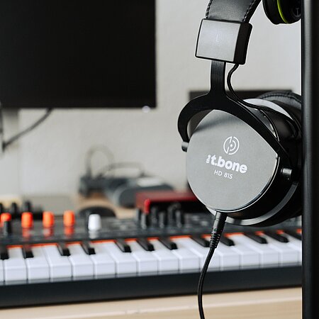 Musikproduktion Kopfhörer mit Keyboardmixer im Hintergrund