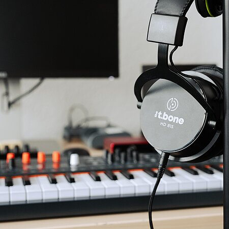 Musikproduktion Kopfhörer mit Keyboardmixer im Hintergrund