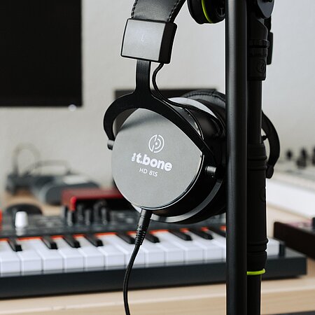 Musikproduktion Kopfhörer mit Keyboardmixer im Hintergrund