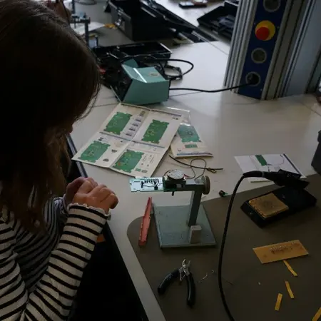 Mädchen beim Löten des Spiels "Heißer Draht"