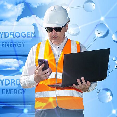 Ingenieur mit Laptop vor Wasserstofftanks