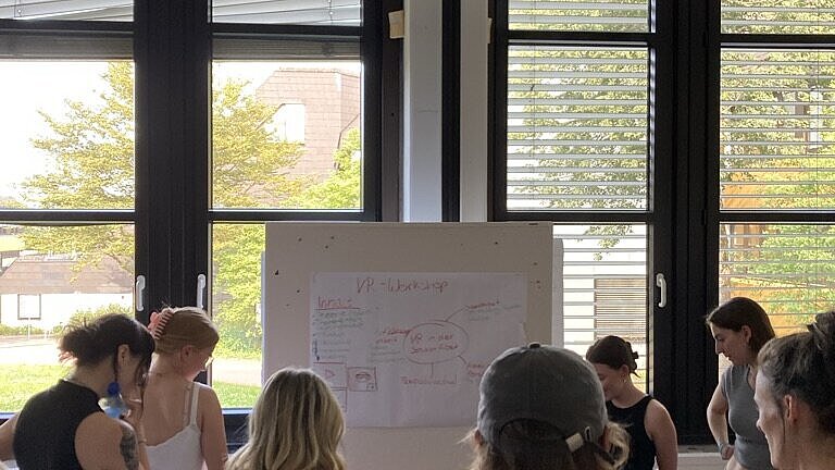 Gruppe Studierender schaut sich ein Plakat an 