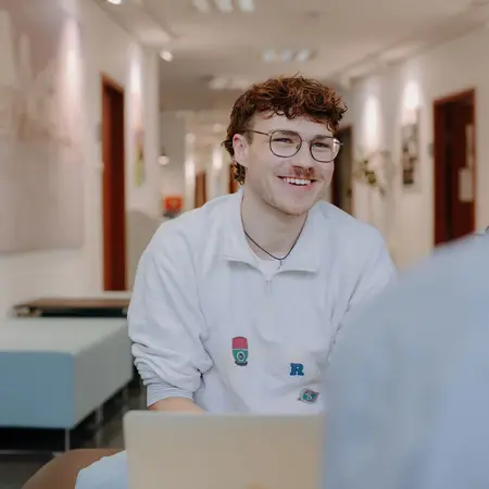Frontansicht eines Studenten, der sich mit seinem Gegenüber im Gespräch befindet