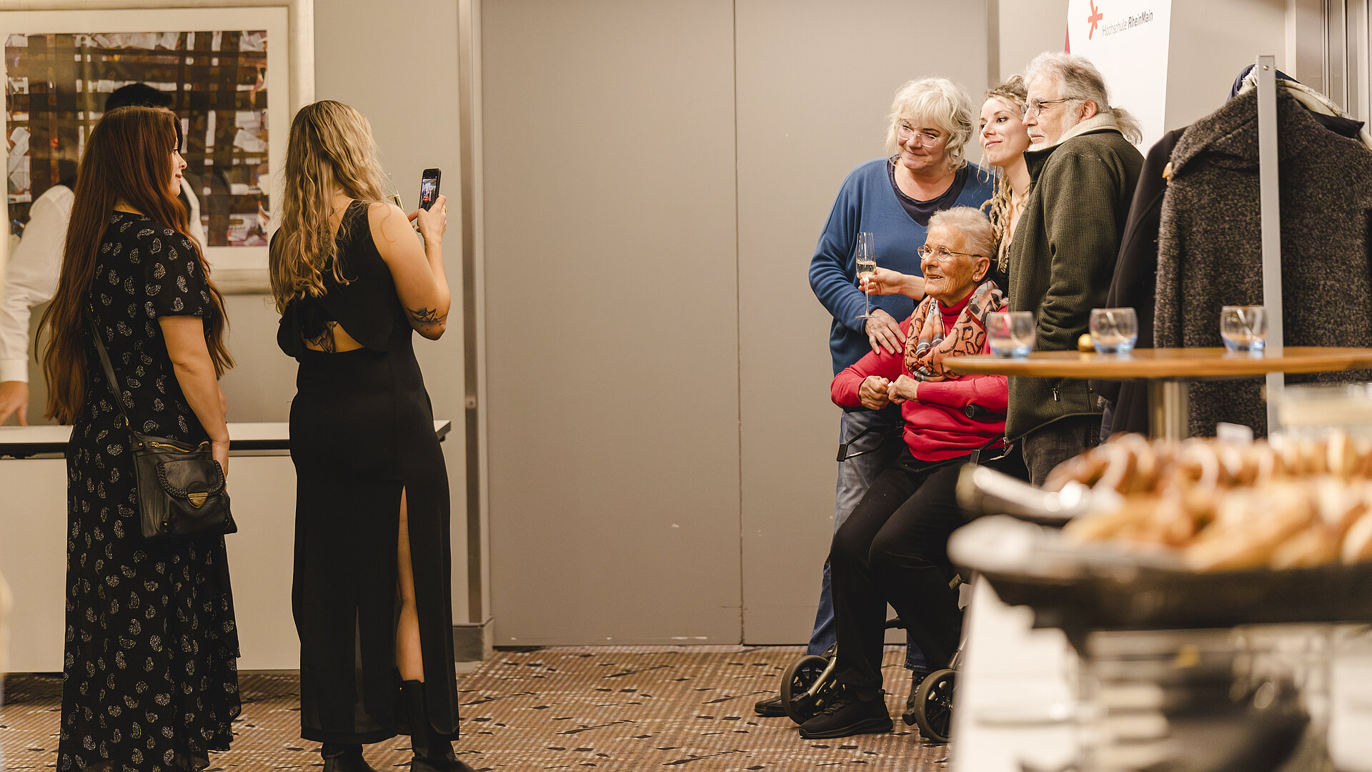 Frauen machen ein Bild von Männern, die vor einem Fotohintergrund posieren 