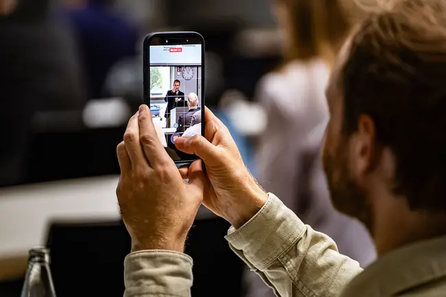 Ein Teilnehmer des Mobile Media Forums 2025 filmt einen Vortrag mit seinem Smartphone.