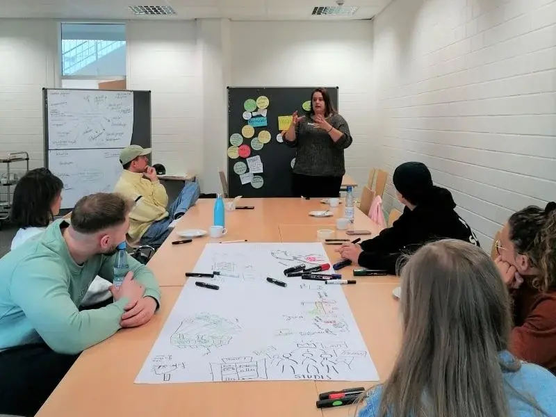 Teilnehmende vom Vernetzungskongress sitzen gemeinsam an einem Tisch