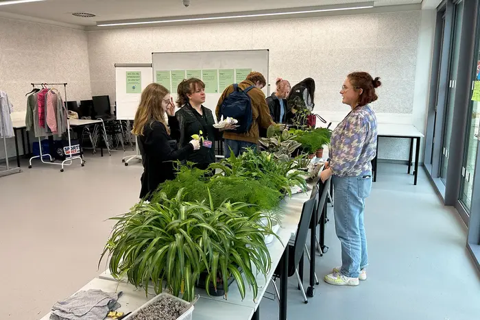 Besucher:innen der Veranstaltung stehen an Stand der Planzentauschbörse.