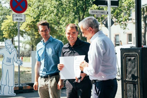 Tarek Al-Wazir, Hessischer Staatsminister für Wirtschaft, Energie, Verkehr und Wohnen (re.) überreicht die Urkunde des GFB-Zukunftspreises an Prof. Sascha Luippold (Mitte).