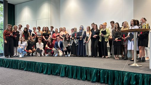 Eine große Gruppe von Personen steht auf einer Bühne und posiert für ein Gruppenfoto.