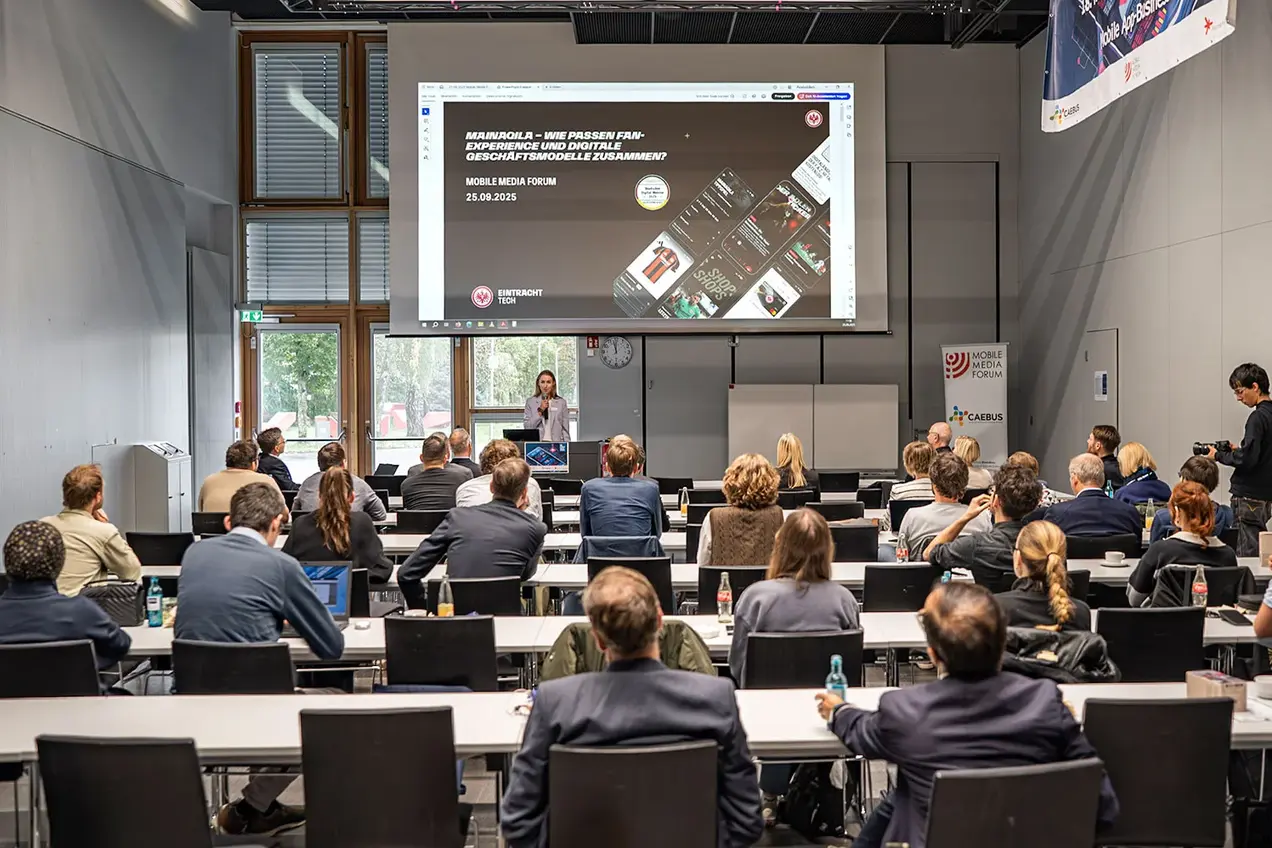 Pauline Frese von EintrachtTech während ihres Vortrags, über ihr die Startfolie ihrer Präsentation zur App mainaqila