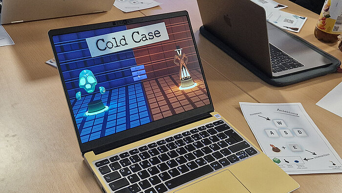 Auf dem Bildschirm eines aufgeklappten Laptops ist die Startseite des Spiels "Cold Case" zu sehen