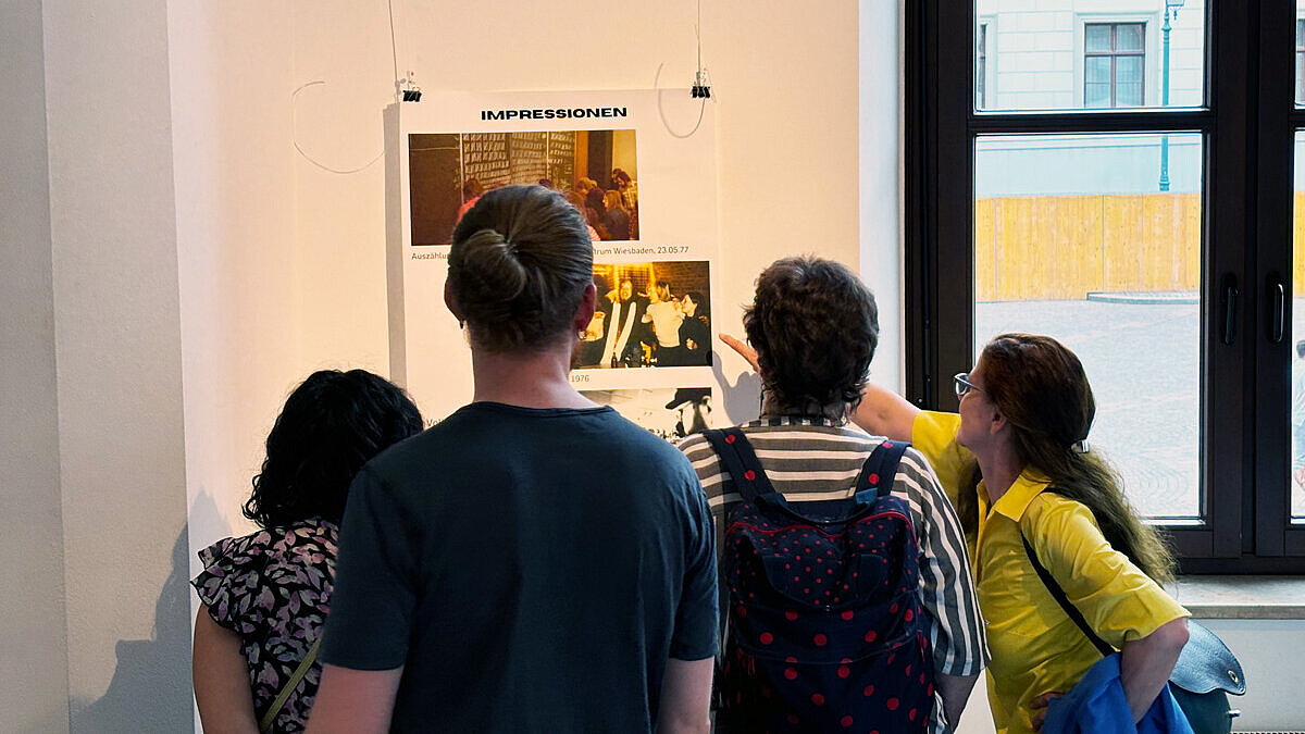 Besucher:innen der Vernissage betrachten Fotos