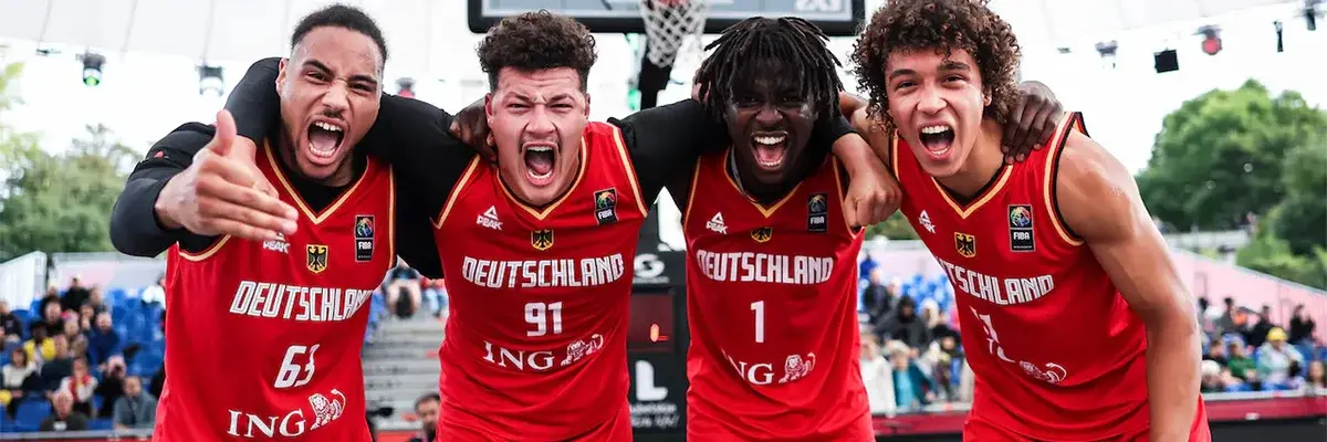 Vier junge Männer posieren für ein Gruppenbild auf einem Basketballplatz