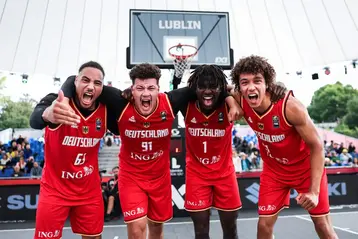 Vier junge Männer posieren für ein Gruppenbild auf einem Basketballplatz