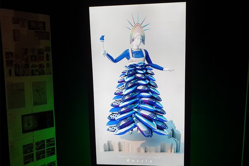 Blick auf einen großen Bildschirm, der eine animierte Person in einem kunstvoll gestalteten Outfit zeigt.