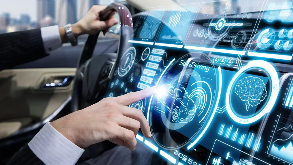 Ein Fahrer in einem modernen Auto bedient ein hochauflösendes digitales Display. Das Display zeigt Informationen zu selbstfahrenden Funktionen und anderen Fahrzeugdaten. Der Fahrer tippt auf das Display, während sich eine Stadtlandschaft im Hintergrund erstreckt.