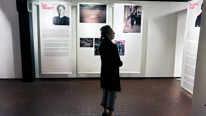 Eine Person steht in der Fotoausstellung „Heiße! Quellen!“ im sam.