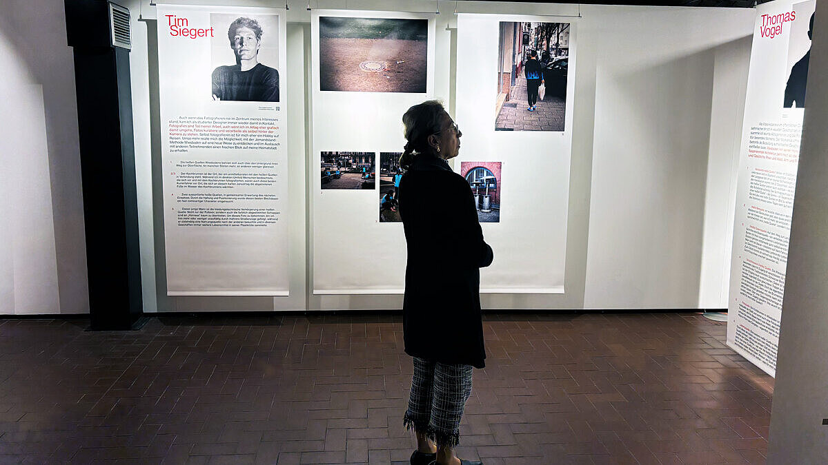 Eine Person steht in der Fotoausstellung „Heiße! Quellen!“ im sam.