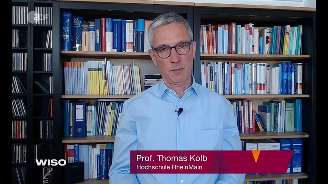 Professor Thomas Kolb steht vor einem Bücherregal und spricht in die Kamera. Er trägt ein hellblaues Hemd und eine Brille. Unter ihm steht sein Name und der Hinweis auf die Hochschule RheinMain.